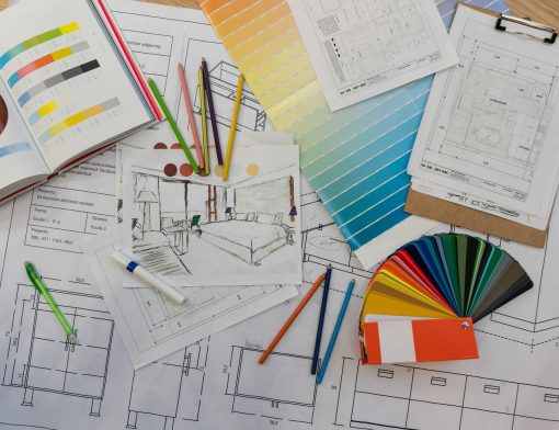 Mesa com materiais do profissional de Design de Interiores, como lápis, projetos e paleta de cores.